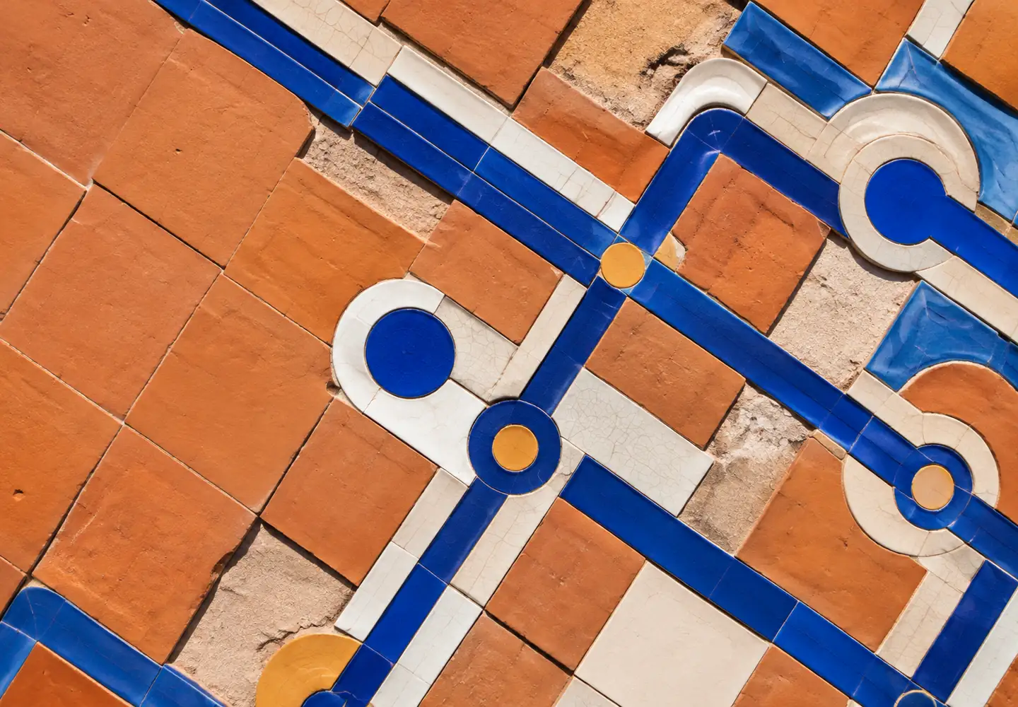 Mosaico de azulejos terracota, blancos y azules convertido en un trazado conductor geométrico